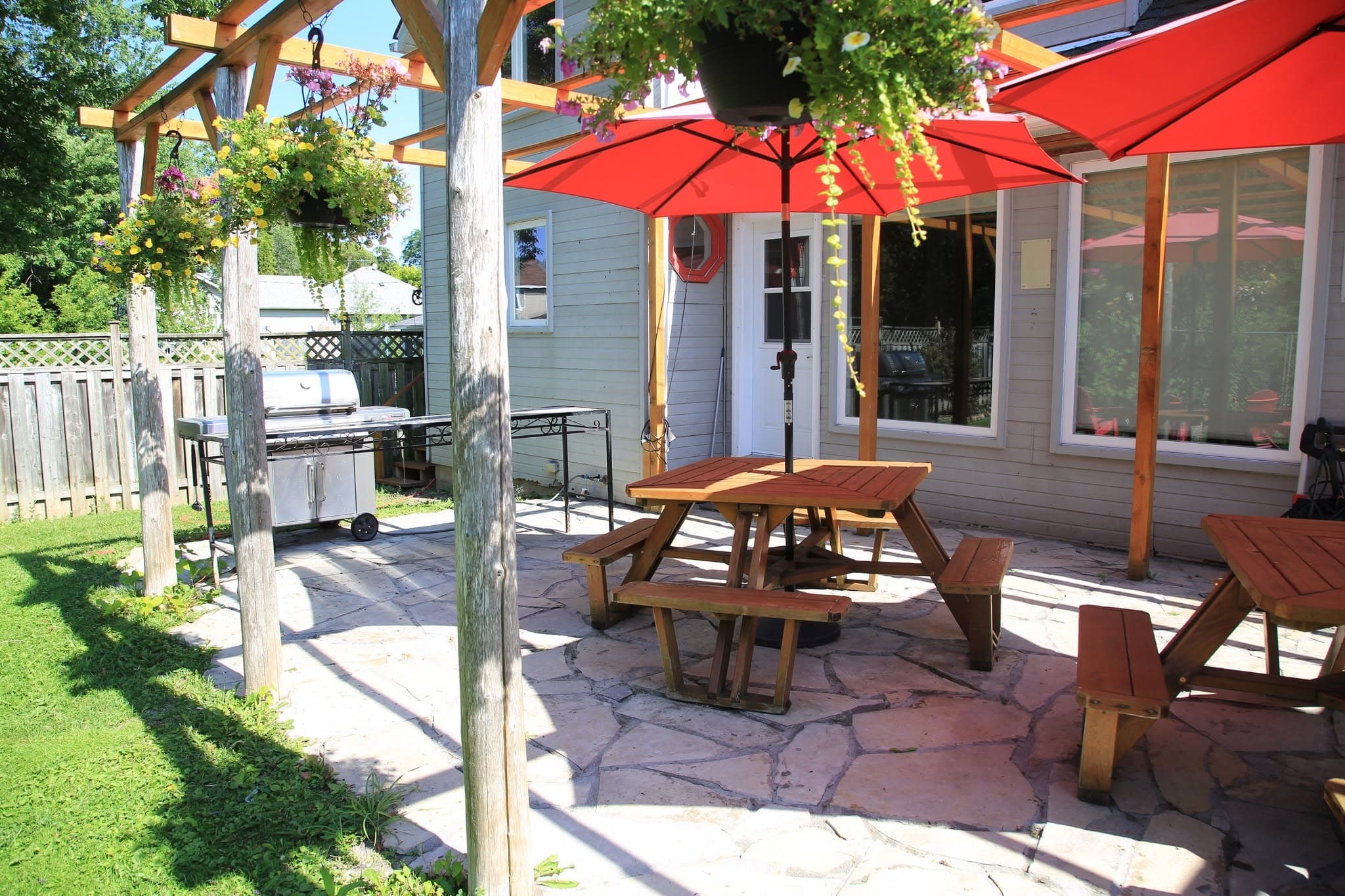 Cedar picnic table under a red umbrella on the flagstone patio